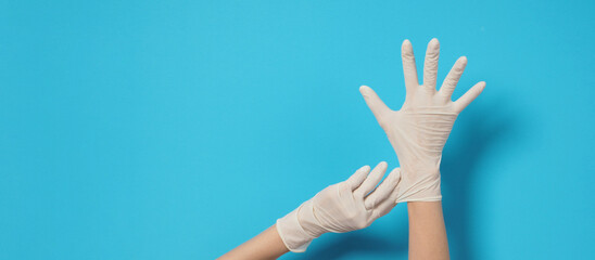 Two hand is wearing white surgical gloves or latex gloves on a blue background.