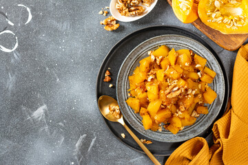 Traditional Turkish dish of baked pumpkin with sugar and walnuts Kabak tatlisi in a blue plate on a culinary background. Delicious healthy dessert top view from the copyspace	