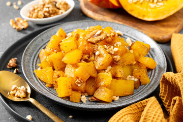 Traditional Turkish dish of baked pumpkin with sugar and walnuts Kabak tatlisi in a blue plate on a culinary background. Delicious healthy dessert closeup	