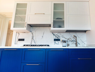 Modern kitchen clean interior design. Luxury blue and white furniture of kitchen with marble tiled backsplash.