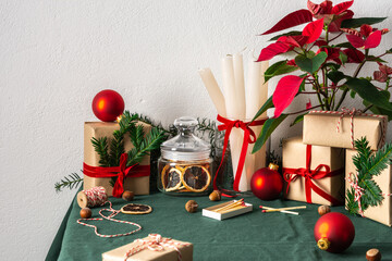 Festive decorated Christmas or New Year's table, spruce branches and Poinsettia flower, candles and Christmas balls, hazelnuts and gift boxes