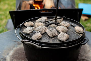 Dutch oven camp cooking with coal briquettes beads on top. Campfire