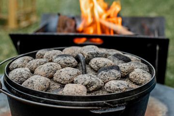 Dutch oven camp cooking with coal briquettes beads on top. Campfire