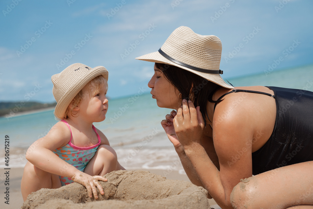 Wall mural girl with her big sister building sand castle on the beach