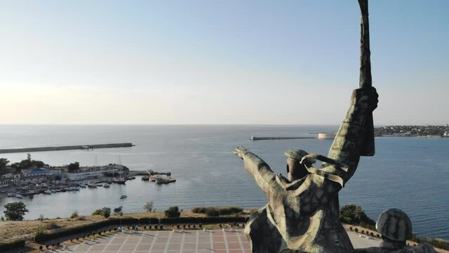Aerial shot of soldiers monument on seashore. Drone flying above city square with beautiful seascape at background. View to historic sculpture in urban park