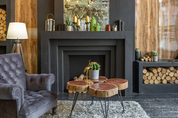 dark brutal interior of sitting room decorated with wooden logs. yellow and grey soft armchairs, huge arc window and fireplace