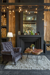 dark brutal interior of sitting room decorated with wooden logs. yellow and grey soft armchairs, huge arc window and fireplace