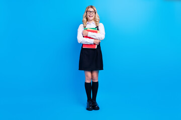 Full body photo of happy positive young girl hold hands notebooks wear long socks isolated on blue color background