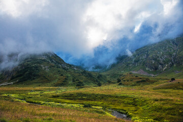 Green mountain Valley in the mountains of Sochi, Russia. Picturesque view, wild flowers. Clouds and blue sky. Krasnaya Polyana.