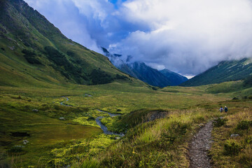 Green mountain Valley in the mountains of Sochi, Russia. Picturesque view, wild flowers. Clouds and blue sky. Krasnaya Polyana.