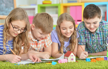 Fototapeta premium Children lying on floor drawing with pencils