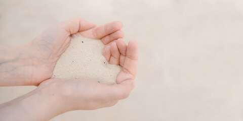Women's hands hold white beach sand.
