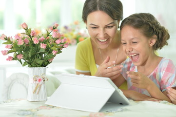 happy mother and daughter using tablet together at home