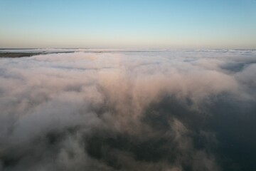 Aerial view of large river with fog above the water.  Colorful landscape with forest in low clouds, river, meadow in fog, orange sky with sun in the morning. .Top view. Nature