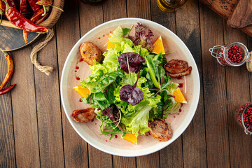 Salad with roasted duck greens and oranges mix on a wooden background