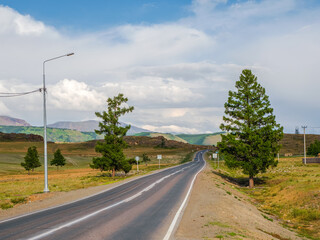 Asphalt road in the autumn mountains. Chuysky tract and a view of the North Chuysky Mountain range in the Altai, Siberia, Russia.