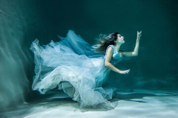 Girl under water in a chic wedding dress. like a mermaid