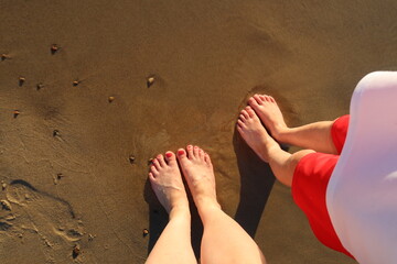 Feet in the beach sand. Mother and baby feet on the beach. View from above