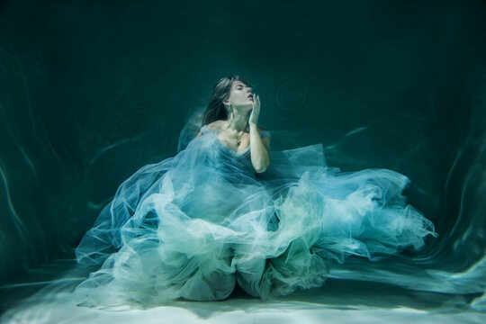 underwater photography. Girl mermaid. model in water in a beautiful dress swims like a fish.In a blue flying dress