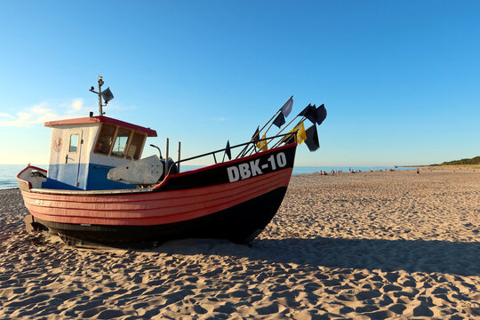 Fishing boats with DBK sign docking on the beach. Sunny summer evening on the Dabki beach, Poland. Dabki, Poland - June 28 2021