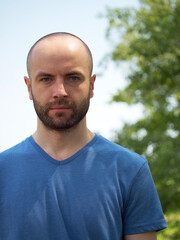 Bust portrait of a white-skinned man. Bald man with a beard.