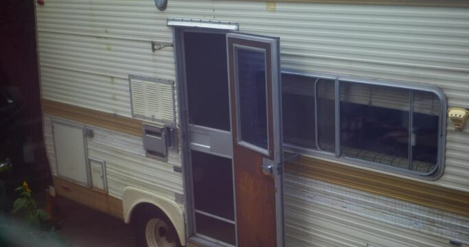 Creepy classic broken down motor home caravan rv with old wood door left wide open. Slow camera pan up, in full Cinema 4k (17x9) real time.