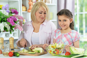 Happy mother and daughter cooking together at kitchen