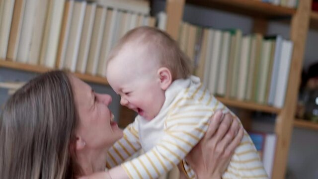 Little infant child laughing having fun and looking in camera. Happy Cheerful Family. Mother And Baby Kissing