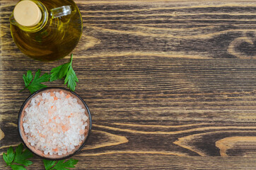 Obraz na płótnie Canvas pink salt and olive oil in the bottle, cooking background with copy space, ingredients on textured wooden cutting board