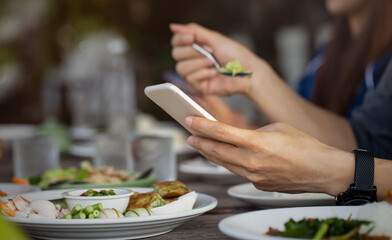 Selective focus of Man having lunch in the restaurant and holding mobile phone in hands  taking picture by smartphone and texting in social media