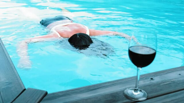 Dead Body of Drowned Young Caucasian Woman Floating in Private Swimming Pool after Drinking Alcohol Wine when Swimming Rack Focus Slow Motion