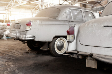 Many rusty abandoned forgotten antique oldtimer old car and motorcycles at junkyard factory storage...