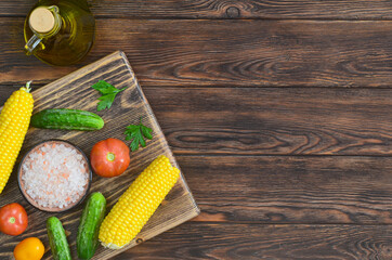 food background and ingredients for cooking summer salad, pink salt mineral, tomato, cucumber, corn, fresh vegetable on wooden table, vitamin for eating