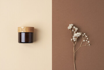 Minimal composition with jar of cosmetic cream and flowers on pastel beige background. Flat lay, copy space