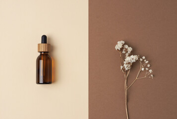Minimal composition with cosmetic bottle and flowers on pastel beige background. Flat lay, copy space.