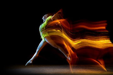 Portrait of young girl, rhythmic gymnastics artist in action isolated on dark studio background...