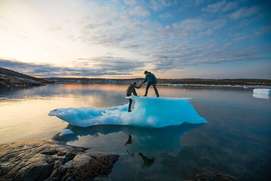 Friends help one another on to an iceberg.