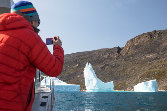 Tourist takes photograph of icebergs, Arctic Ocean.