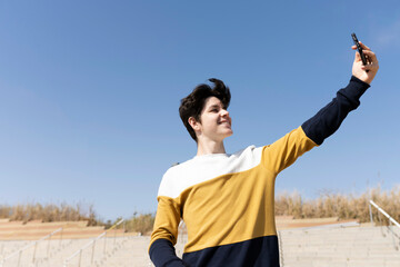 happy smiling nice young man or teenage boy taking selfie in city