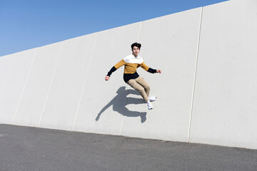 Young man jumping on the urban wall background