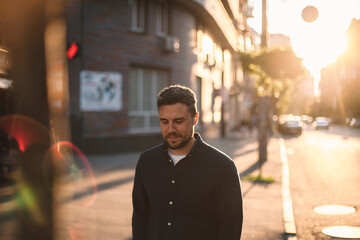 Happy thoughtful man walking on street in city during summer