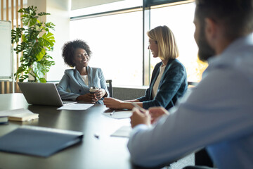 Cheerful diverse colleagues talking during meeting