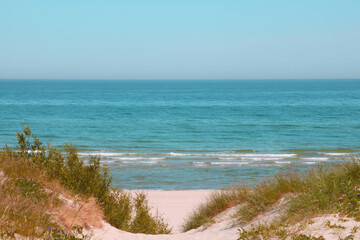 View of the sandy shore against the background of the sea or the ocean with blue sky.