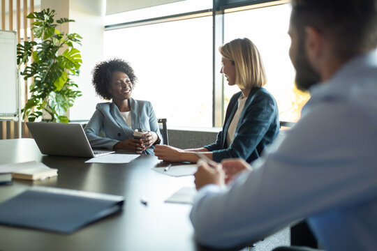 Cheerful diverse colleagues talking during meeting