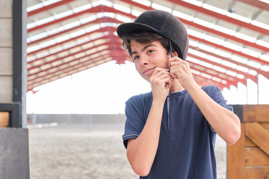 Teenage boy putting a riding helmet on his head.
