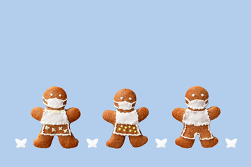 Cute gingerbread family with protective face masks and butterflies, isolated, blue background. Greeting card, copy space for text. Creative concept in coronavirus (COVID-19) time