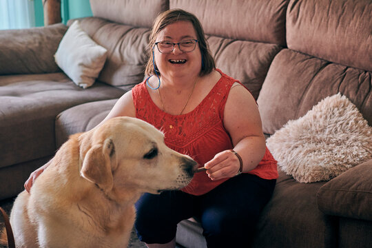 Adult woman with down syndrome has fun with her dog at home