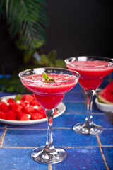 Watermelon refreshing summer frozen cocktail smoothie with watermelon slices and pieces on the background