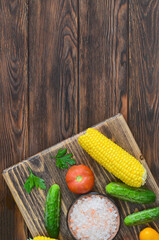 food background and ingredients for cooking summer salad, pink salt mineral, tomato, cucumber, corn, fresh vegetable on wooden table, vitamin for eating