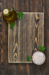 pink salt and olive oil in the bottle, cooking background with copy space, ingredients on textured wooden cutting board
